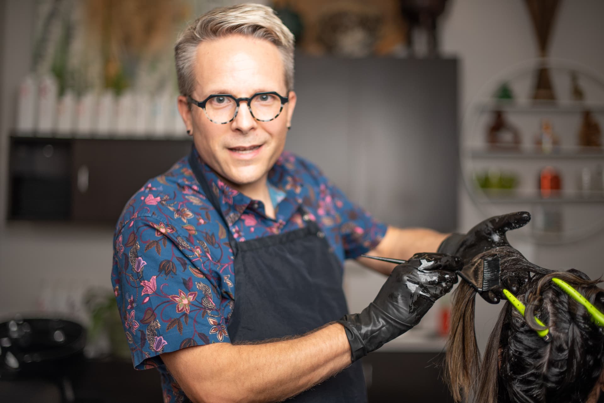 Ray applying hair color with a brush, smiling at the camera.